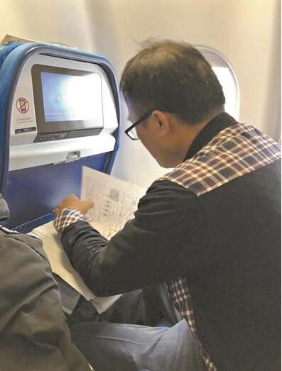 教师出差飞机上改试卷走红 这是经济舱吗？