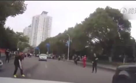 哭笑不得!横跨马路打羽毛球太惊险 汽车从球下穿行