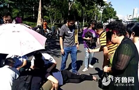 济南一女子飞速骑电动车被甩下 路人挡车遮伞救助